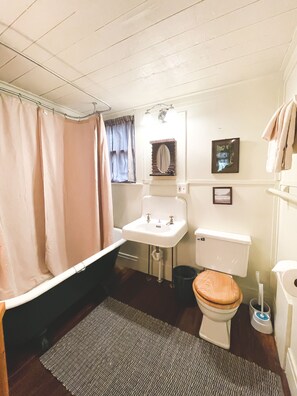 A compact bathroom with a bathtub, sink, toilet, and a small mirror. - Signature Cabin 3 with Lake View (Paul Smiths)