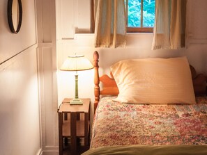 A bedroom with a bed, a nightstand, a lamp, and a window with curtains. - Signature Cabin 3 with Lake View (Paul Smiths)