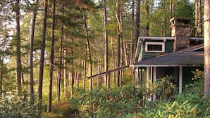 A cabin in a forest with a visible path leading to it. - Signature Cabin 3 with Lake View (Paul Smiths)