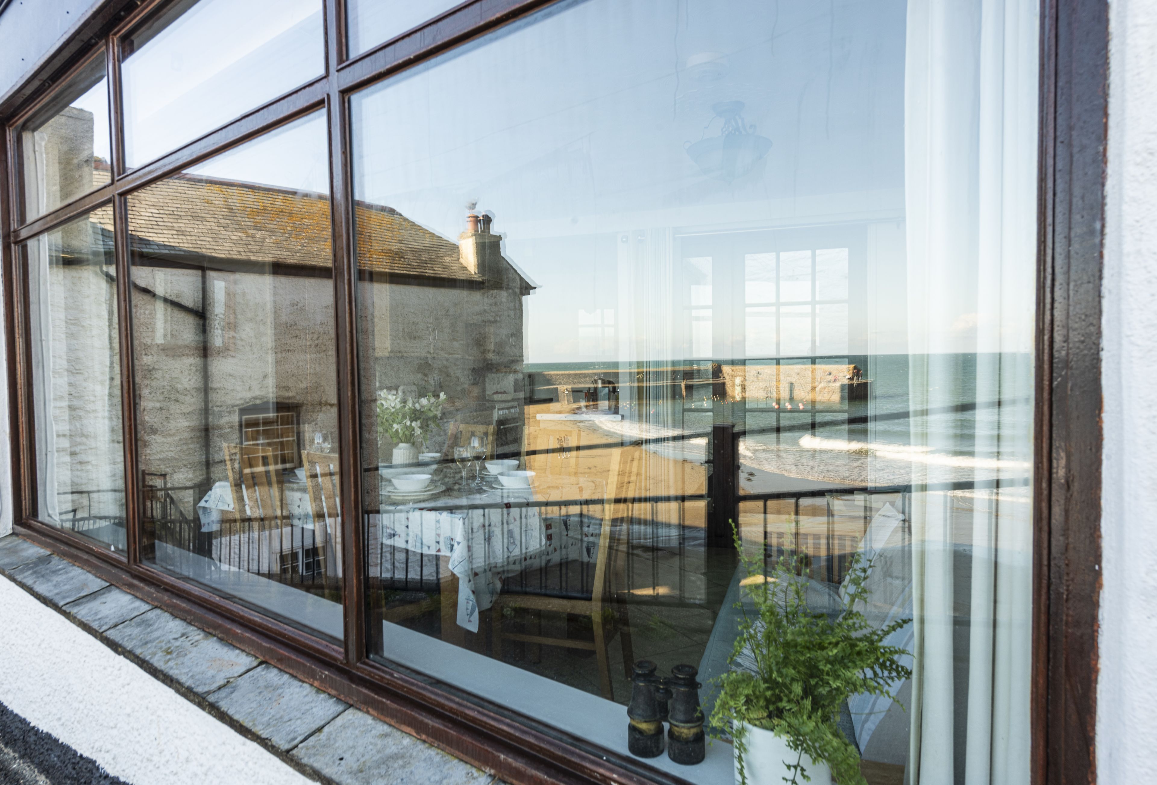 A large window with a view of a dining area, including tables and chairs, and a building in the background.