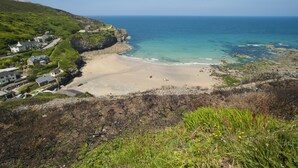 A coastal area with a sandy beach, rocky shoreline, and buildings on a hillside. - A stunning, environmentally friendly holiday haven at Mor Cliff, in an AONB. (Chapel Porth)