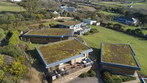 A modern house with a flat roof and a large patio area. - A stunning, environmentally friendly holiday haven at Mor Cliff, in an AONB. (Chapel Porth)