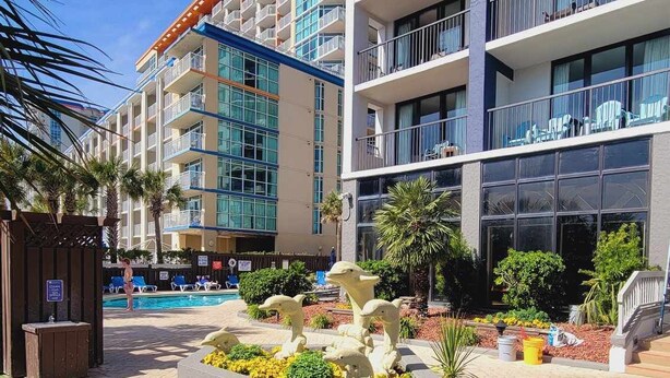 A hotel with multiple balconies, a swimming pool, and a landscaped garden area. - Beautifully Updated Condo in Beachfront Resort.   (Myrtle Beach)