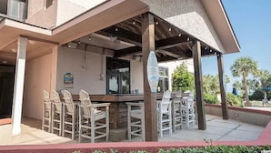 An outdoor bar area with a pool table, multiple chairs, and a covered seating area. - Beautifully Updated Condo in Beachfront Resort.   (Myrtle Beach)