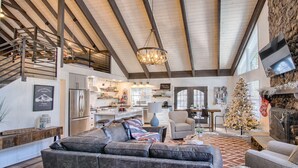 A spacious living area with a high ceiling, a fireplace, a Christmas tree, and a modern kitchen in the background. - #AzStoneCabin- Finest Luxury Cabin In Pinetop- Lakeside! (Pinetop)