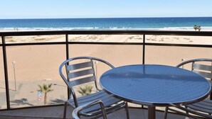 Ein Balkon mit Metalltisch und -stühlen mit Blick auf einen Strand.