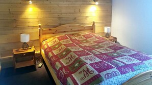 A wooden-paneled room with a bed, two bedside lamps, and a nightstand.