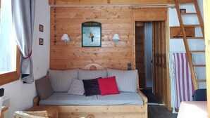 A cozy cabin interior with a wooden bunk bed, a sofa with patterned cushions, a wall-mounted sign, and a ladder. - Le Mucillon 39 - 2-room apartment, close to the ski slopes, facing south (LES AVANCHERS VALMOREL)