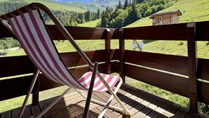 A wooden deck with a striped chair, a wooden fence, and a mountain view. - Le Mucillon 39 - 2-room apartment, close to the ski slopes, facing south (LES AVANCHERS VALMOREL)