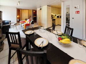 A dining area with a long table set for four, chairs, a fruit bowl, and a kitchen in the background. - Chalet Guldeli by Interhome (Kandergrund)