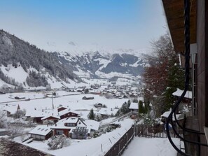 A snowy mountain village with houses and a wooden fence.