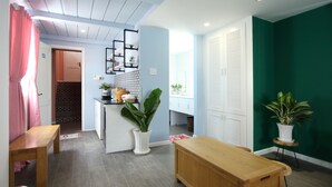 A modern kitchen with a wooden island, a dining area with a wooden table, and a green accent wall. - Sleepbox Hostel Phu Quoc (Phu Quoc)