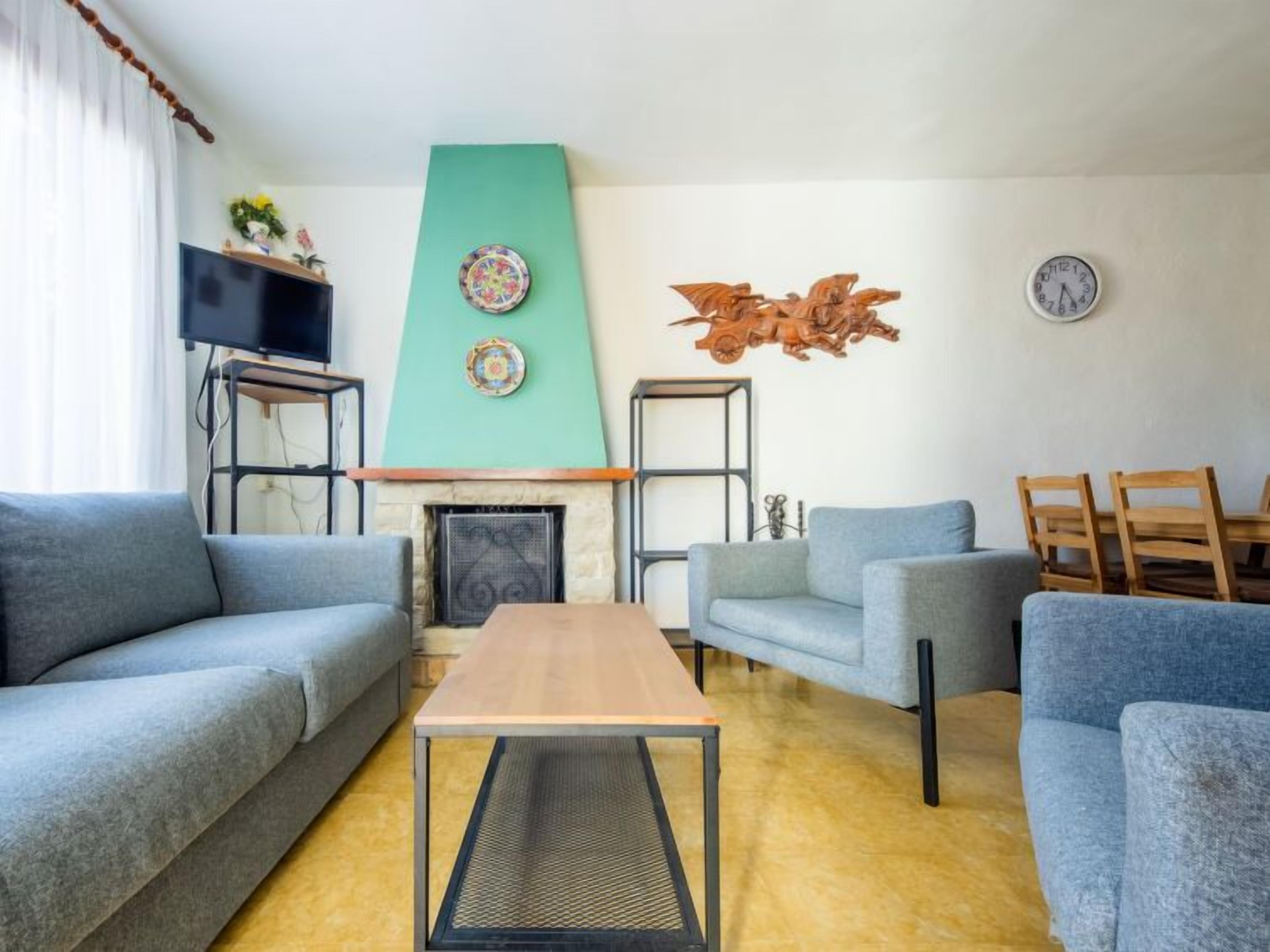A living room with two grey sofas, a wooden coffee table, a fireplace, and decorative plates on the wall.