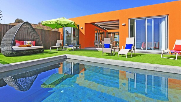 Een modern buitenzwembad met een inbouwzitgedeelte, een overdekte patio en een grote schuifdeur van glas.