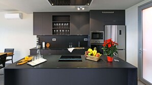 Een moderne keuken met een centraal eiland, geïntegreerde apparatuur en een eethoek met een tafel en stoelen.