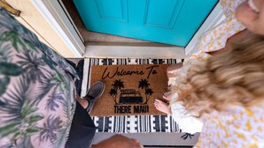 A door mat with a tropical design and the text "Welcome To There Maui."