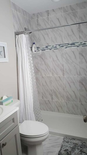 Een bad/douchecombinatie, een haardroger, handdoeken, zeep