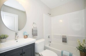 Een bad/douchecombinatie, een haardroger, handdoeken, zeep