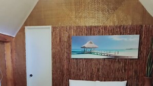 A bedroom with a wooden ceiling, a bed with white bedding, and a painting of a beach scene. - Set amidst lush greenery and azure waters of the Pacific Ocean. (Surigao)