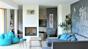 A modern living room with a fireplace, seating area, and artwork on the walls.