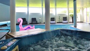 Une piscine intérieure dotée de chaises longues et d’un jacuzzi.
