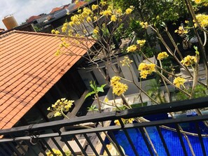 A building with a tiled roof and a balcony with yellow flowers. - Villa Glas (Kerobokan)