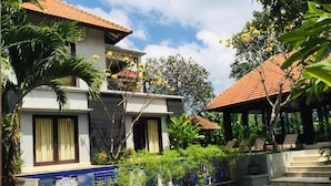 A two-story house with a tiled exterior, a balcony, and a staircase leading to a covered area. - Villa Glas (Kerobokan)