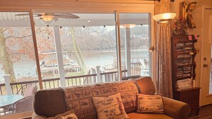 Un salon confortable avec un canapé, un tapis, une bibliothèque et une vue sur un lac.