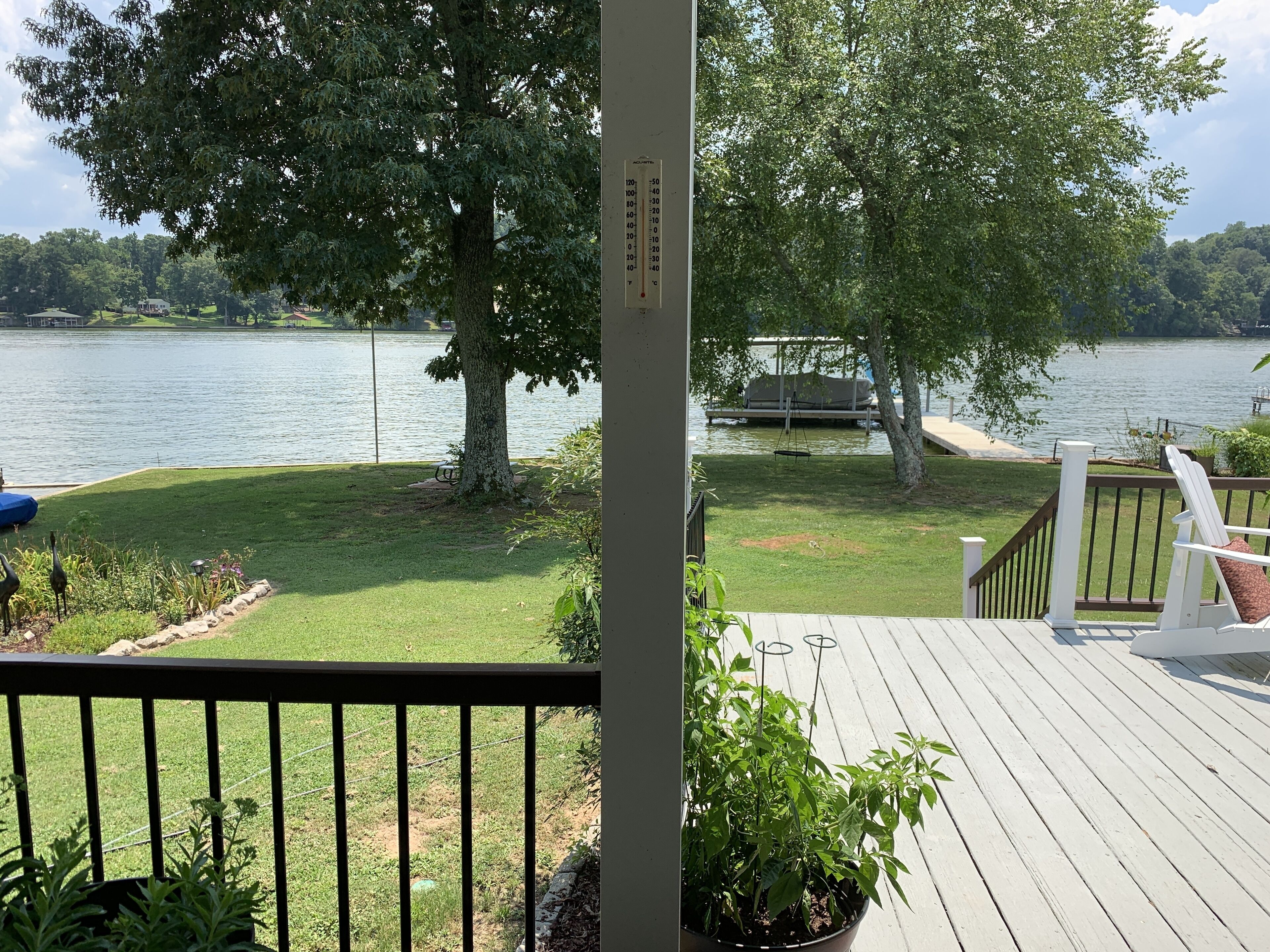 A deck with a view of a lake, a swing, and a bench.