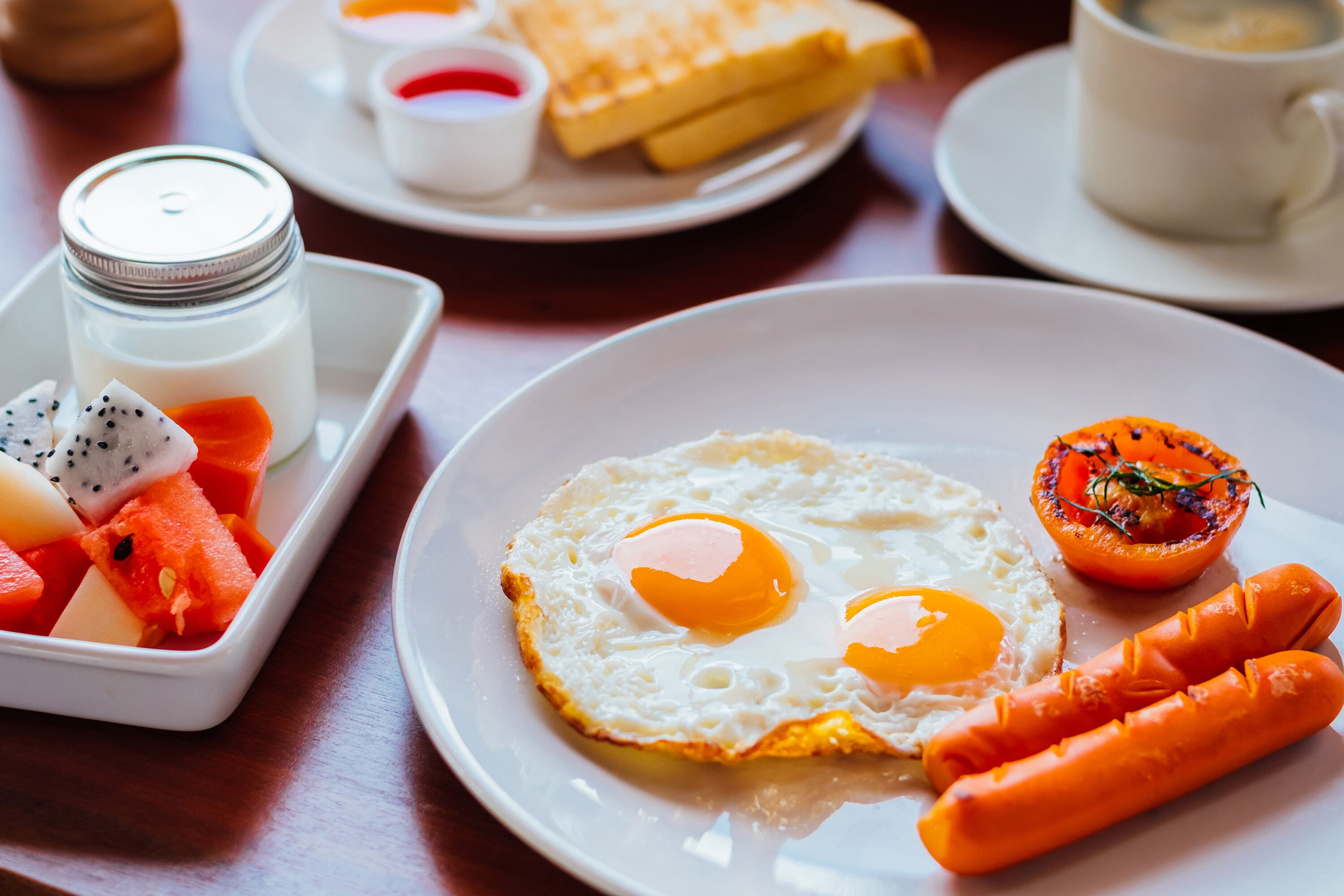A breakfast plate with fried eggs, sausage, and a grilled tomato.