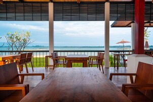 Mesa y sillas de madera en un espacio al aire libre cubierto, con vista al mar.