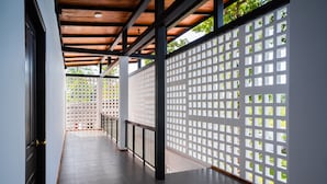 A covered corridor with a wooden ceiling, a tiled floor, and a white lattice partition.