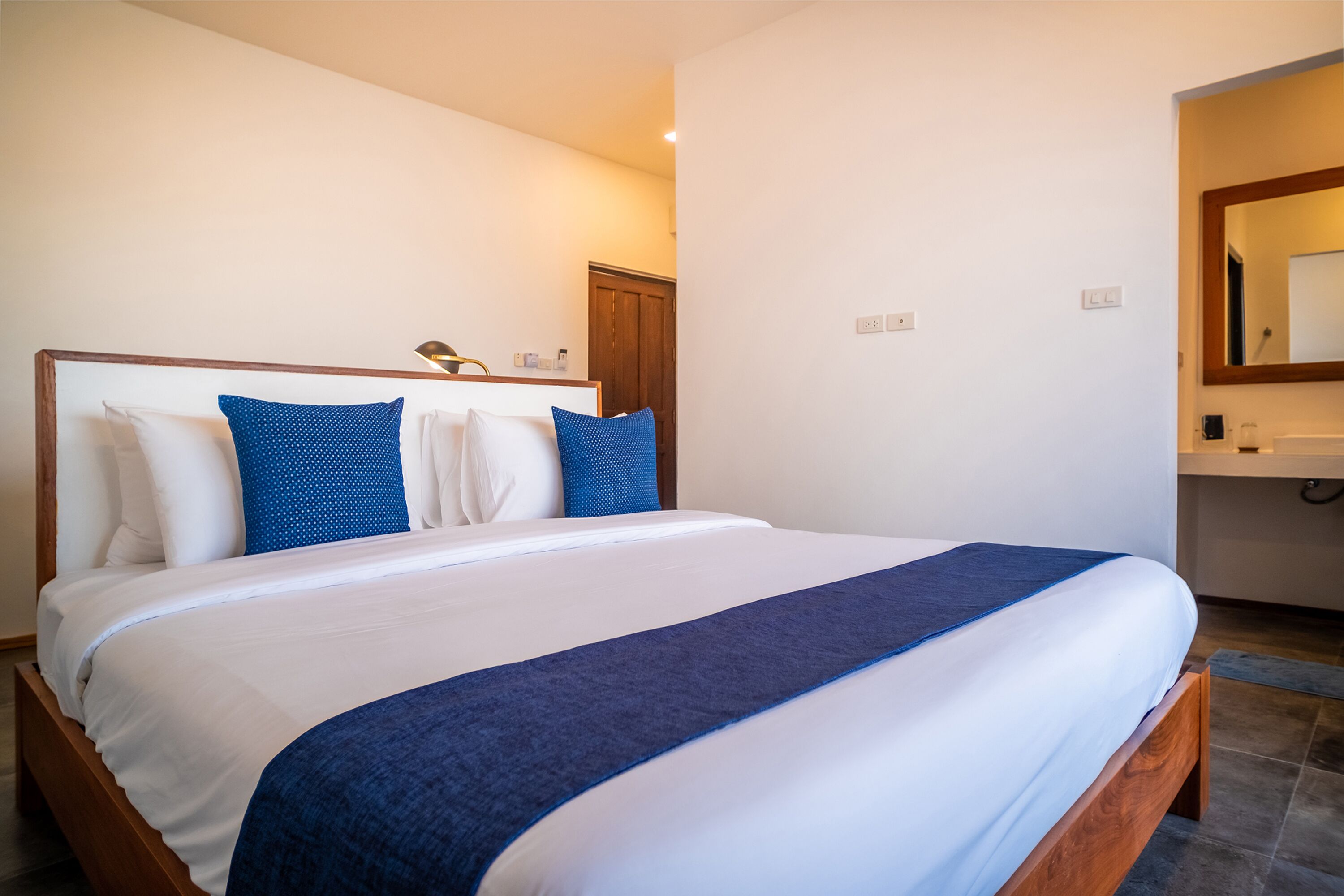 A neatly made bed with a wooden headboard and blue bedding.