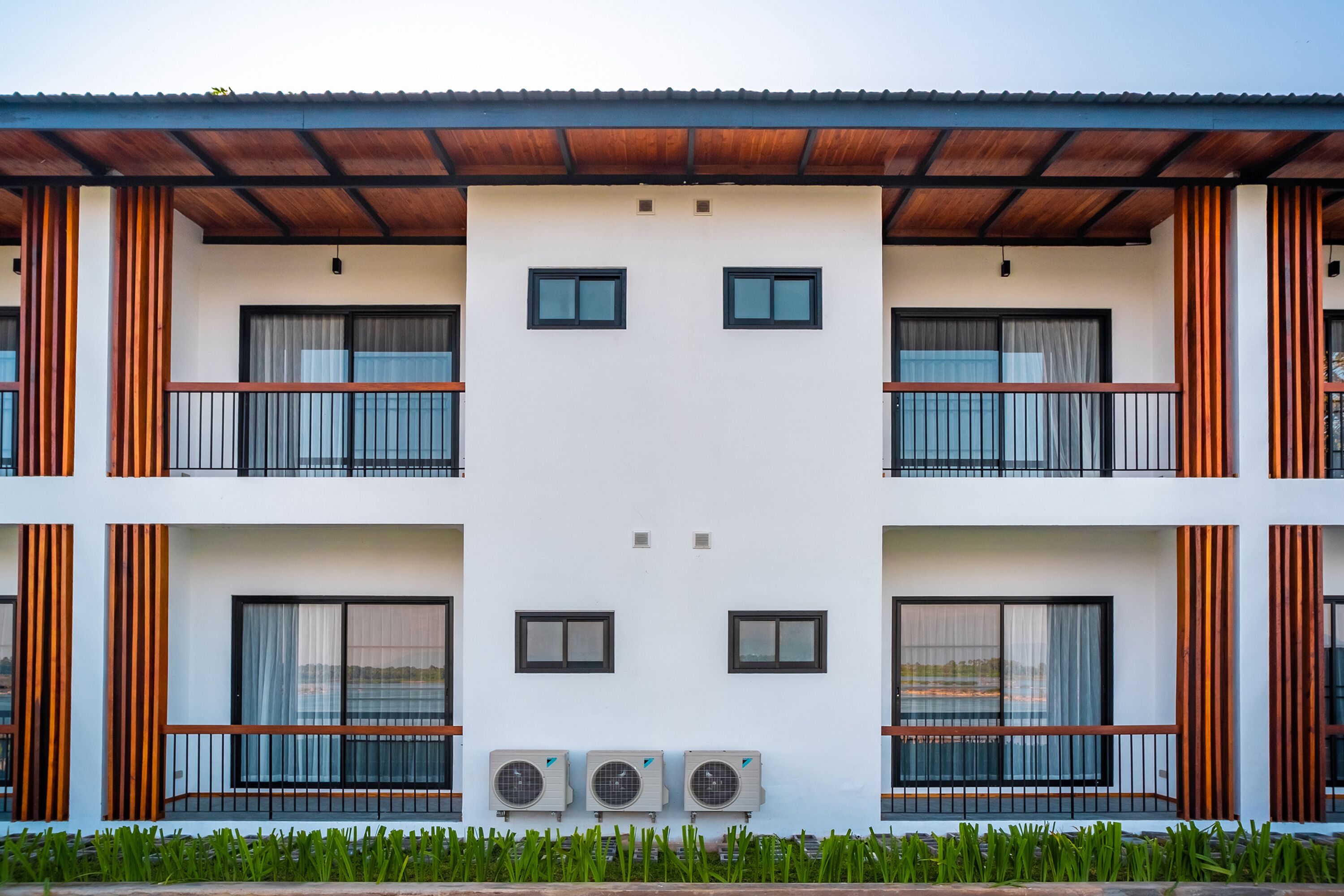 Un edificio moderno con fachada simétrica, ventanas amplias y unidades de aire acondicionado.