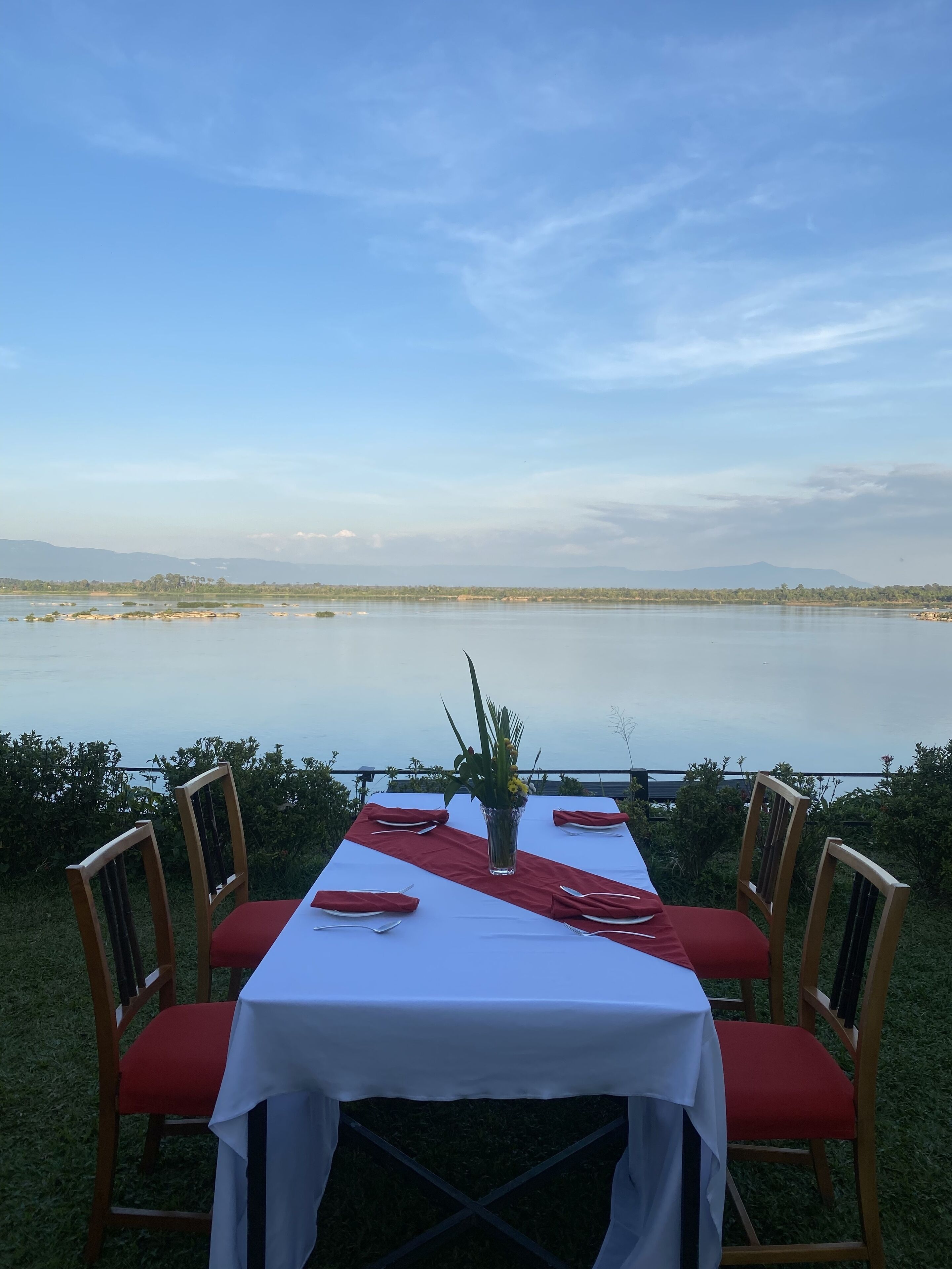 Mesa lista para comer con vista a un lago y montañas distantes.
