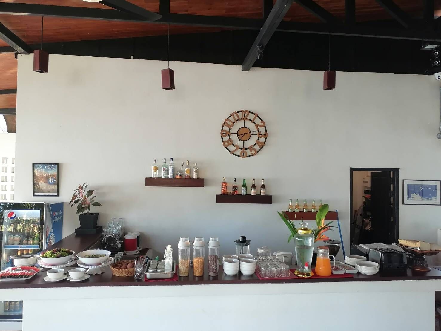 A bar area with shelves of liquor, a clock, and various bar tools.