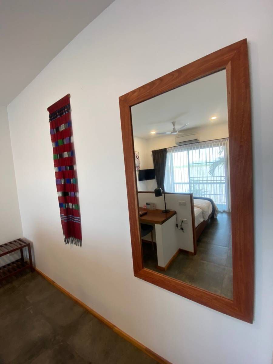 A room with a large mirror, a bed, a desk, and a window with curtains.