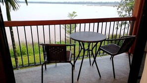 A balcony with a table and two chairs, overlooking a calm body of water. - The Riviera Champasak (Champasak)