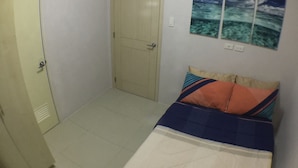 A bedroom with a bed, a door, and a wall with three framed pictures. - Grass homes 2 bedrooms (Bago Bantay)