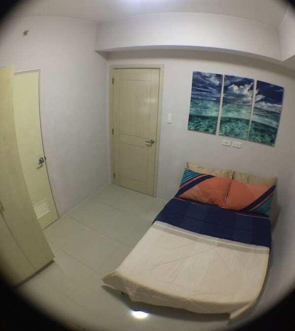 A bedroom with a bed, a door, and a wall with three framed pictures.