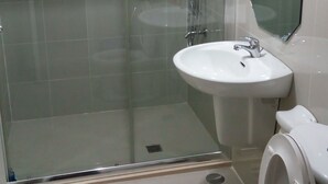A bathroom with a glass-enclosed shower, a sink, and a toilet. - Grass homes 2 bedrooms (Bago Bantay)