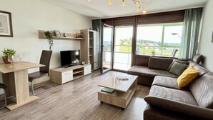Una sala de estar moderna con un sofá, una mesa de centro, un televisor y un comedor con mesa y sillas.