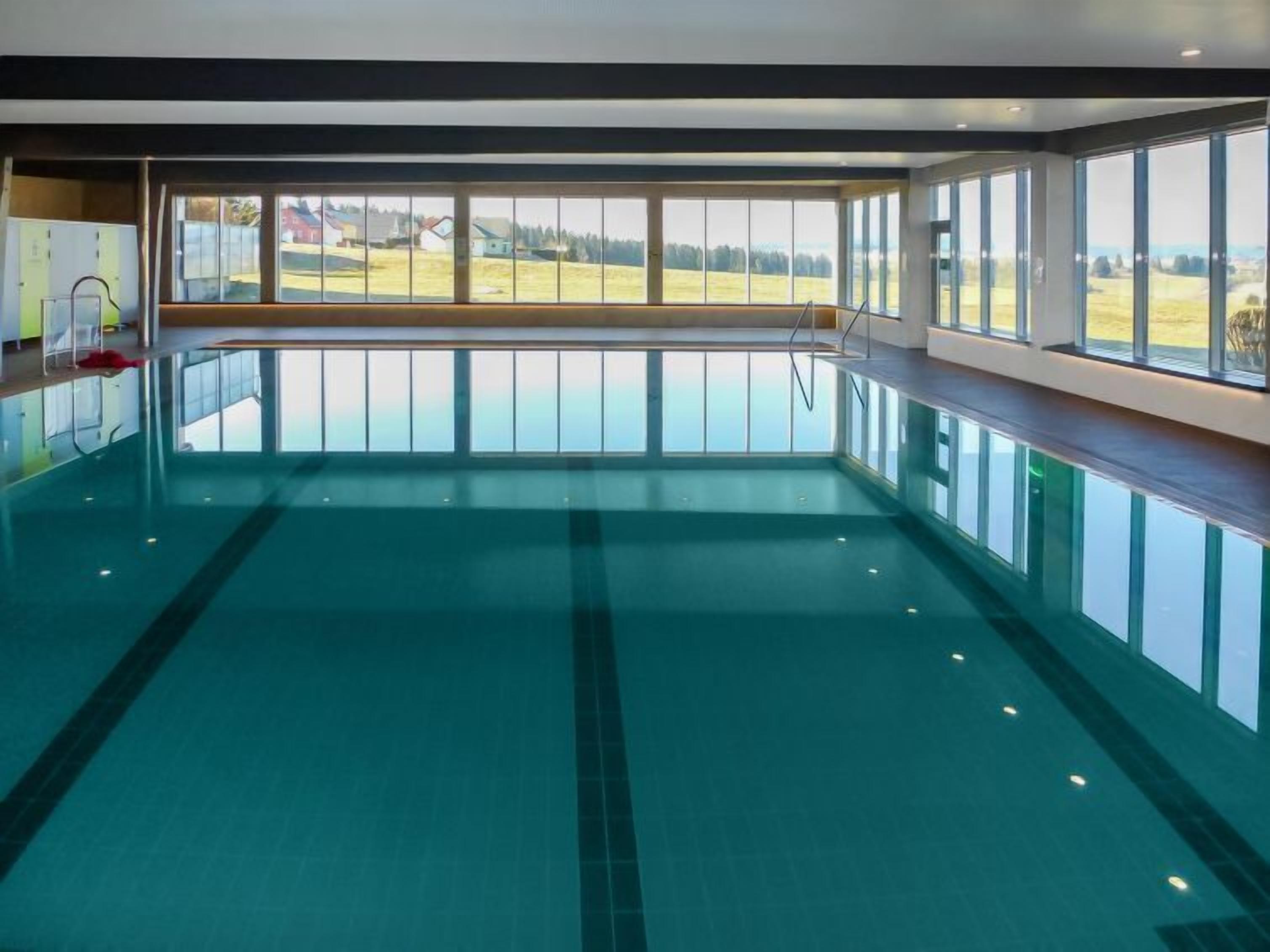 Una piscina interior con vistas despejadas a un paisaje rural a través de amplios ventanales.