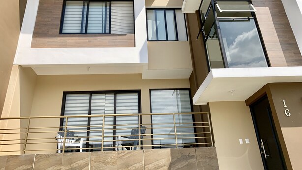 A modern apartment building with multiple balconies, large windows, and a visible door marked with the number 16. - Exclusive Gated Community with HD TV, Air Conditioning, Cable and Netflix  (Nuevo Cuscatlán)