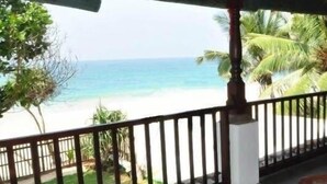 A covered outdoor area with a view of the beach, a table with food items, and a railing.