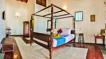 A four-poster bed with a marble floor, a wooden cabinet, and a small stool.