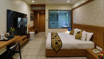 A hotel room with a bed, a desk, a TV, a bathroom, and a view through a large window.