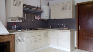 A kitchen with white cabinets, a gas stove, and hanging utensils.