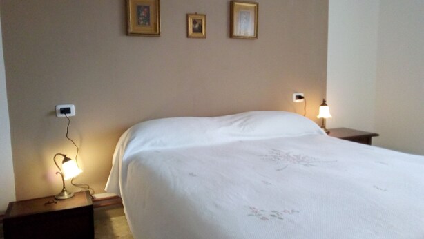 A hotel room with a large bed, two bedside tables, and two wall-mounted lamps.