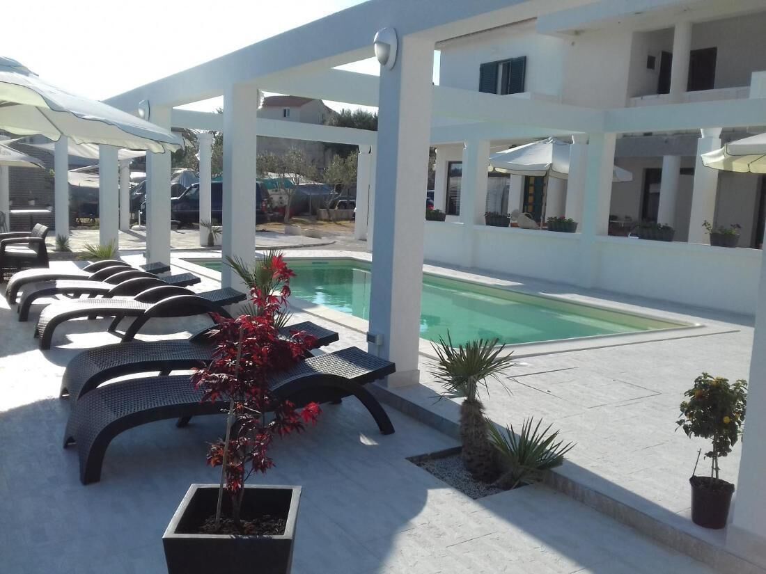 Un área junto a la piscina con sillones de descanso, una piscina pequeña y plantas en macetas.